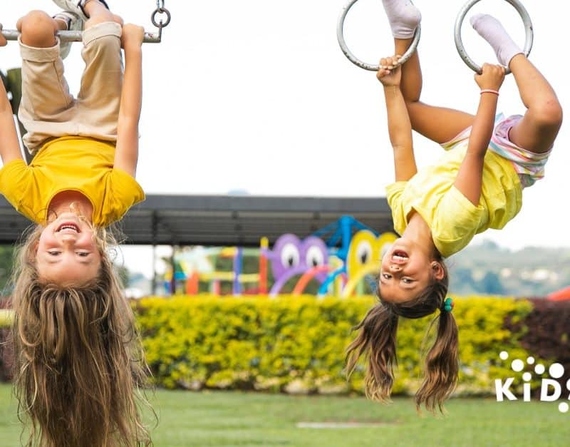 Two happy children playing together on a colorful playground at KidsPark Daycare in California.